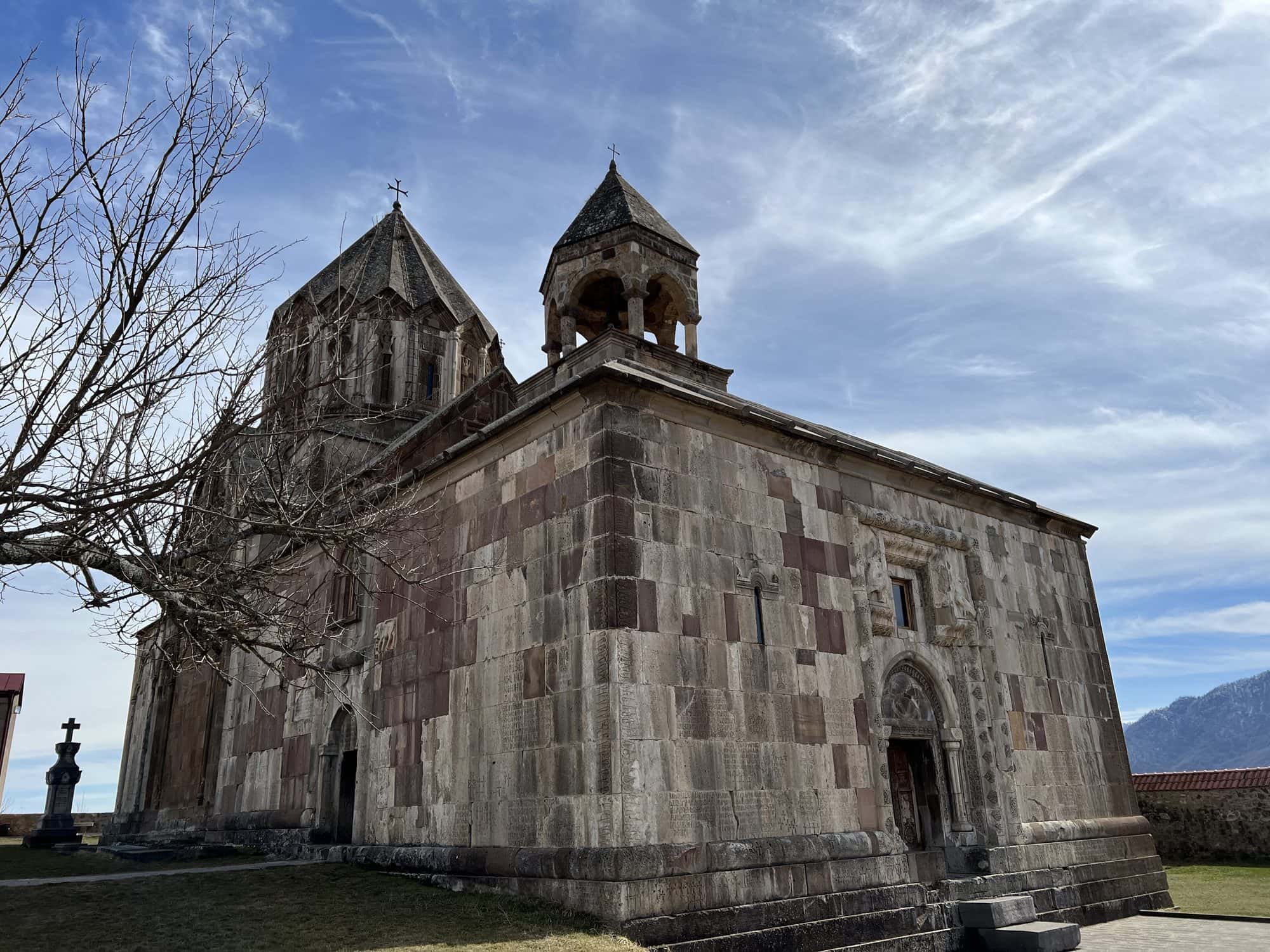 Domed stone cathedral with a conical umbrella roof inside a walled monastery on a hilltop