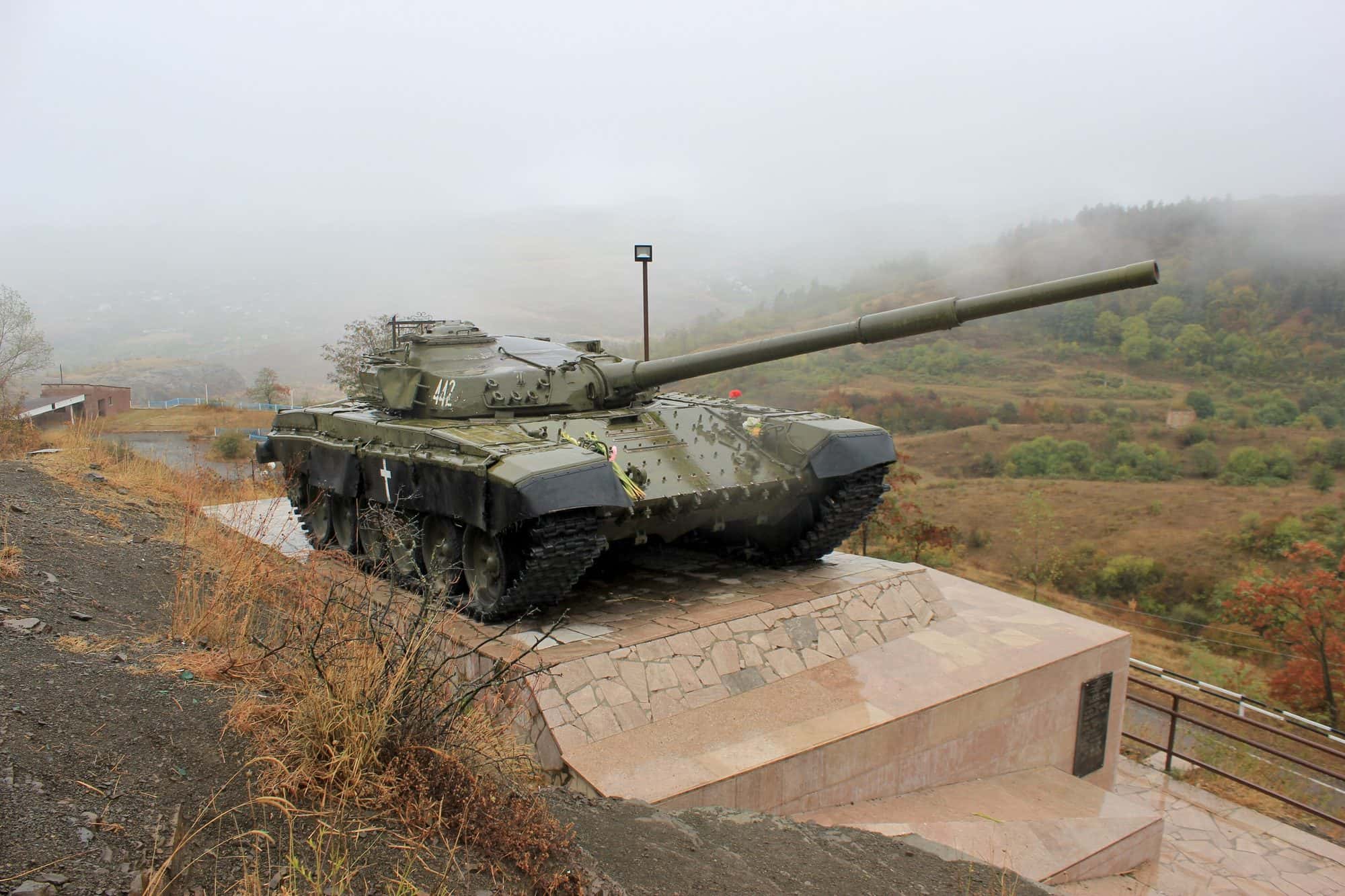 A T 72 tank mounted on a concrete plinth beside a road, serving as a war memorial near Shushi