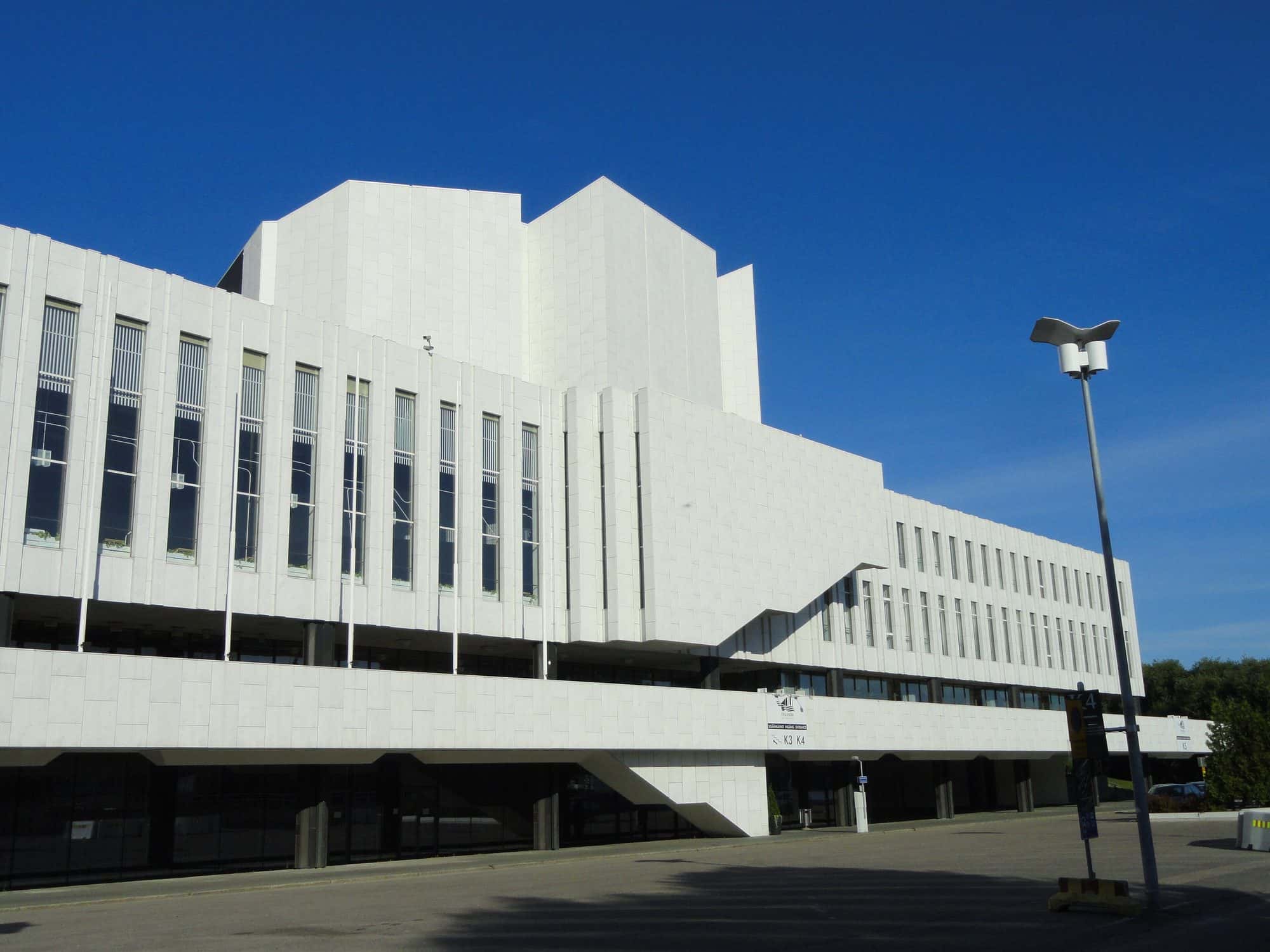 White marble modernist concert and congress building beside water in Helsinki under a clear sky