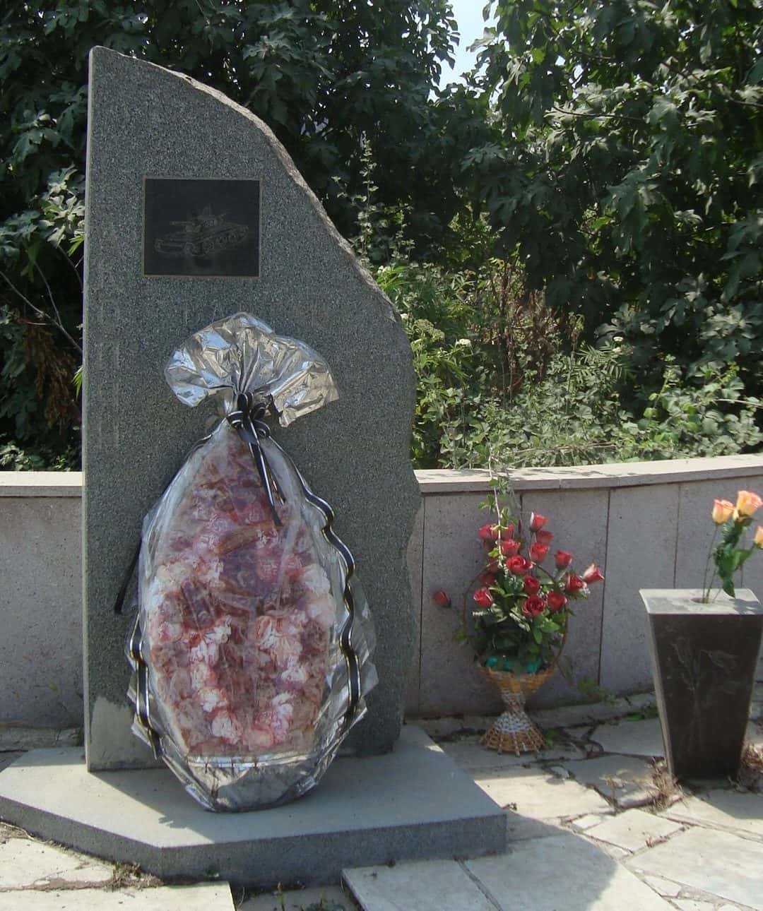 Stone memorial with Armenian inscription commemorating the dead of Maragha, standing among trees