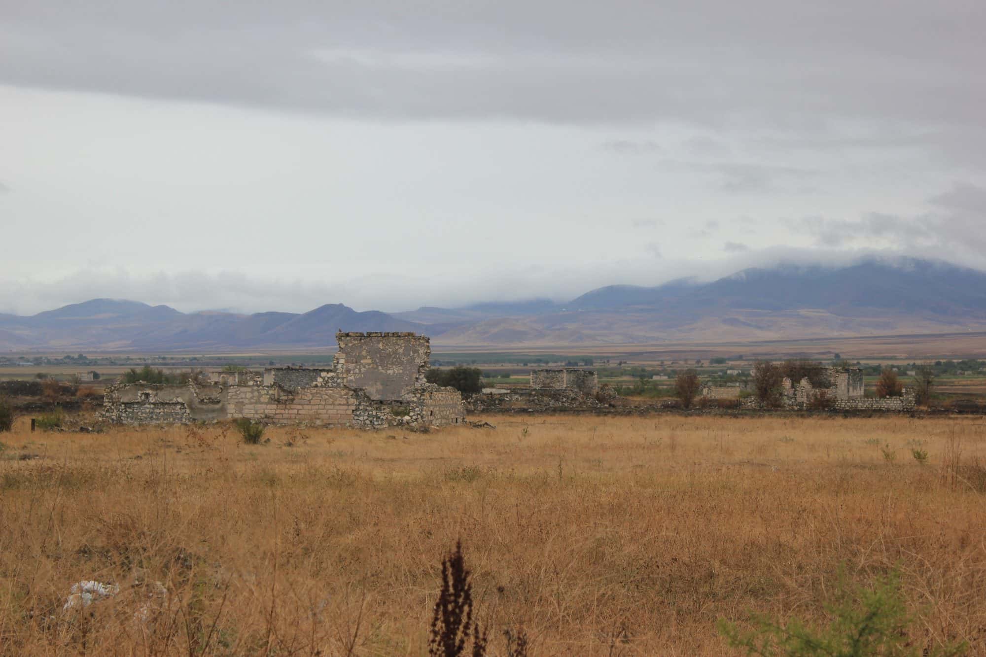 Roofless ruined buildings and overgrown streets of an abandoned city under a wide sky