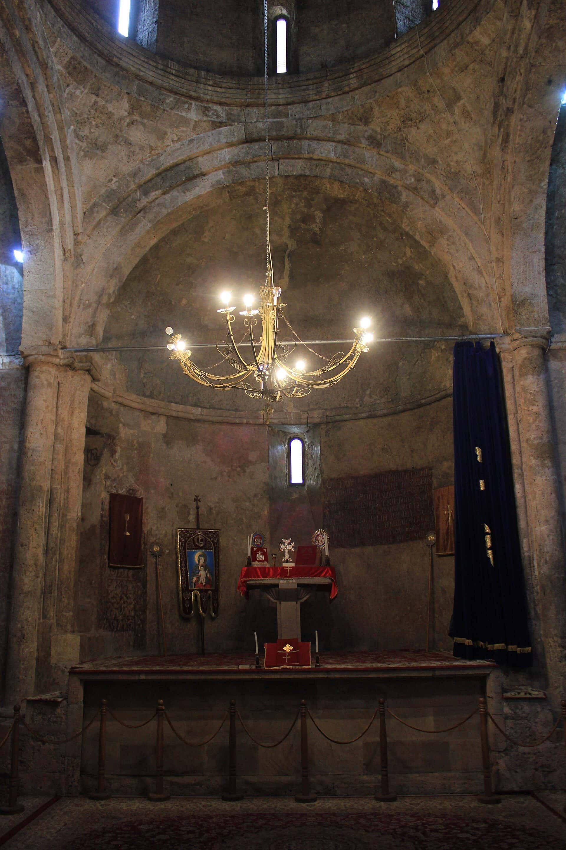 Medieval Armenian monastery of stone with a domed church, standing on a green mountainside