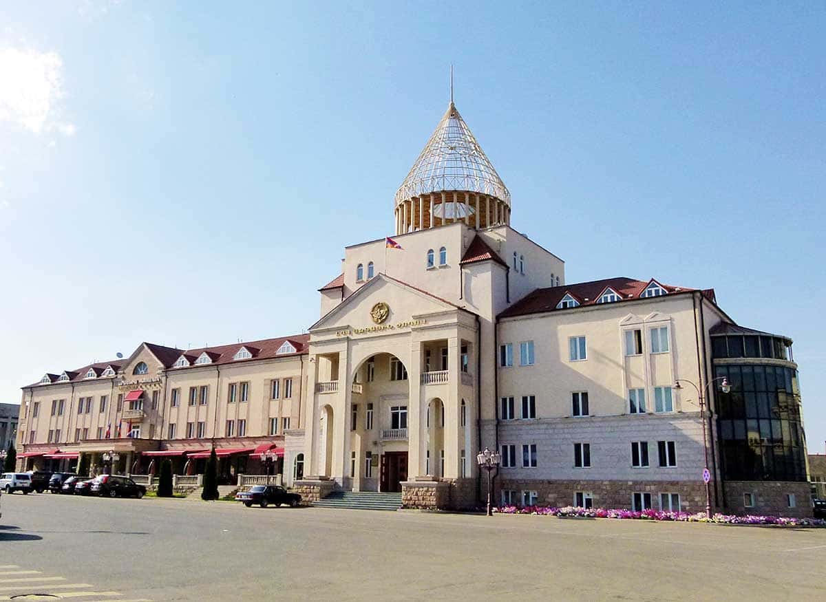 Parliament building in Stepanakert seen from the street, with a flag above the portico