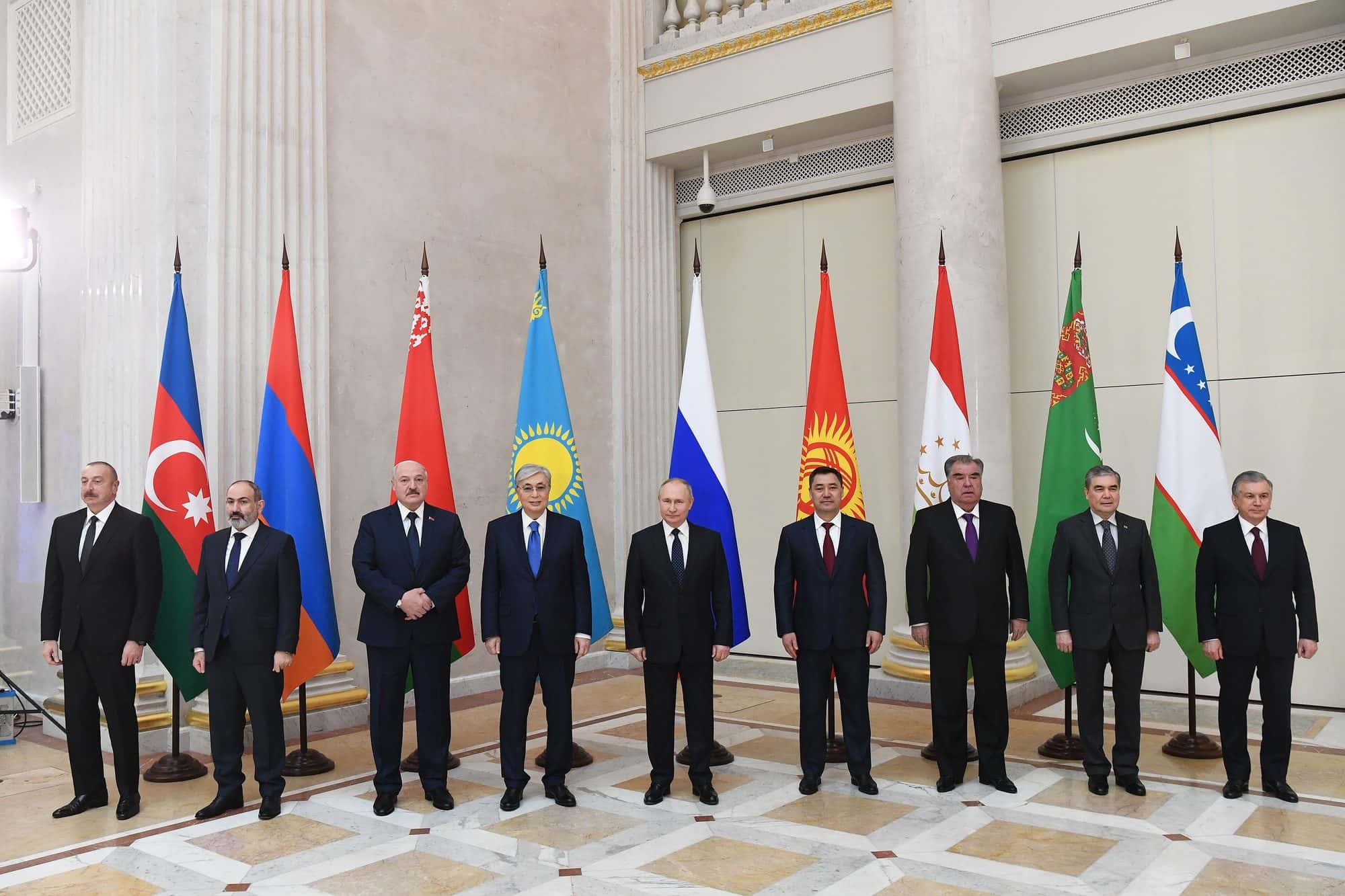 Leaders standing before national flags, Aliyev at far left beside Pashinyan