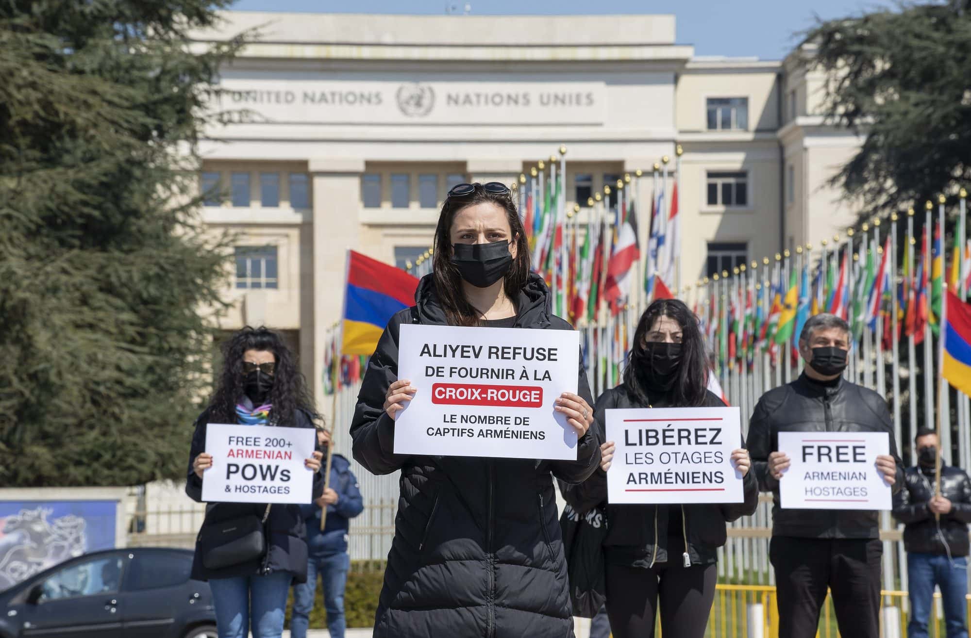 Four masked protesters holding placards calling for the release of Armenian prisoners outside the UN building