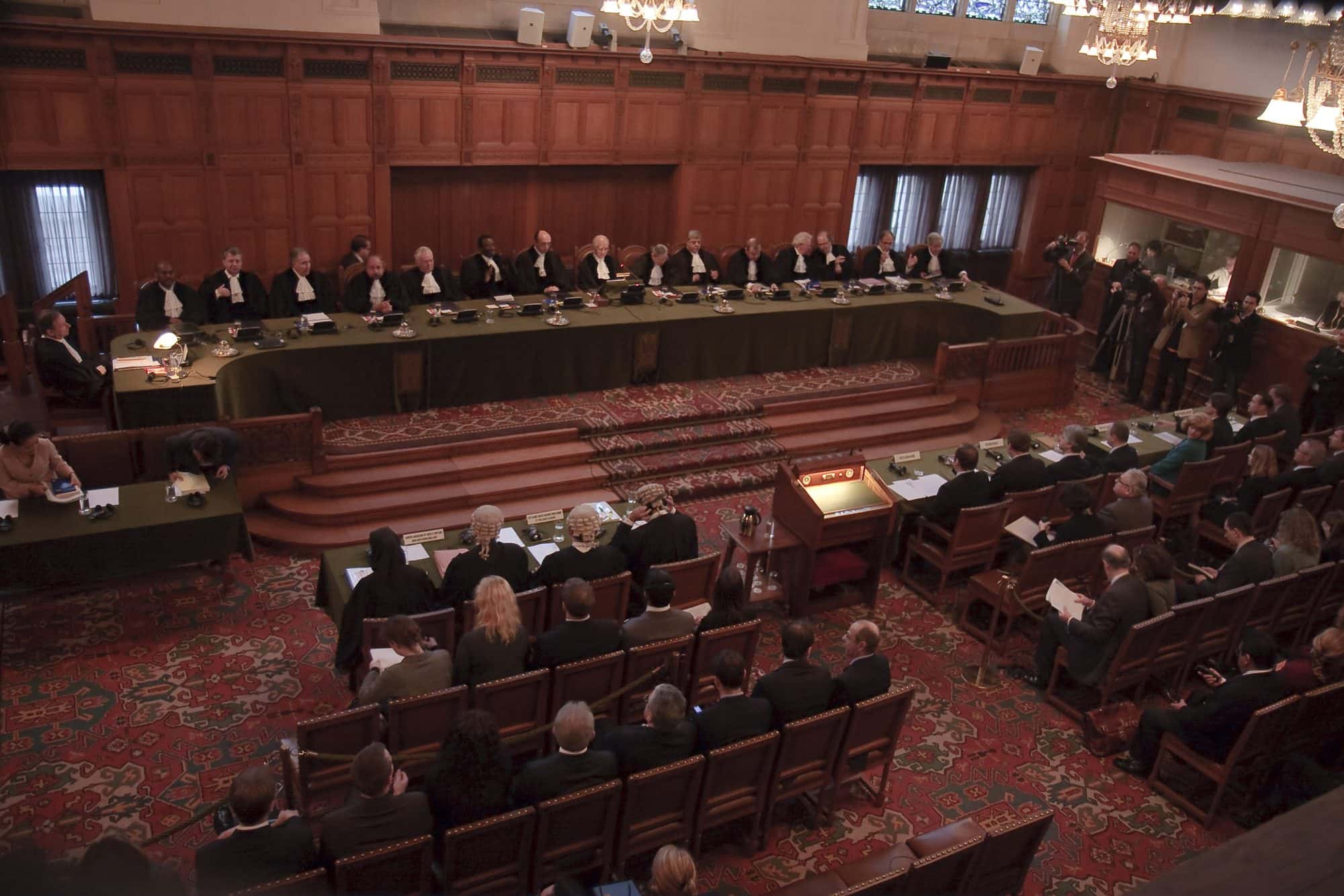 Ornate wood panelled courtroom with stained glass windows and a long raised judges' bench