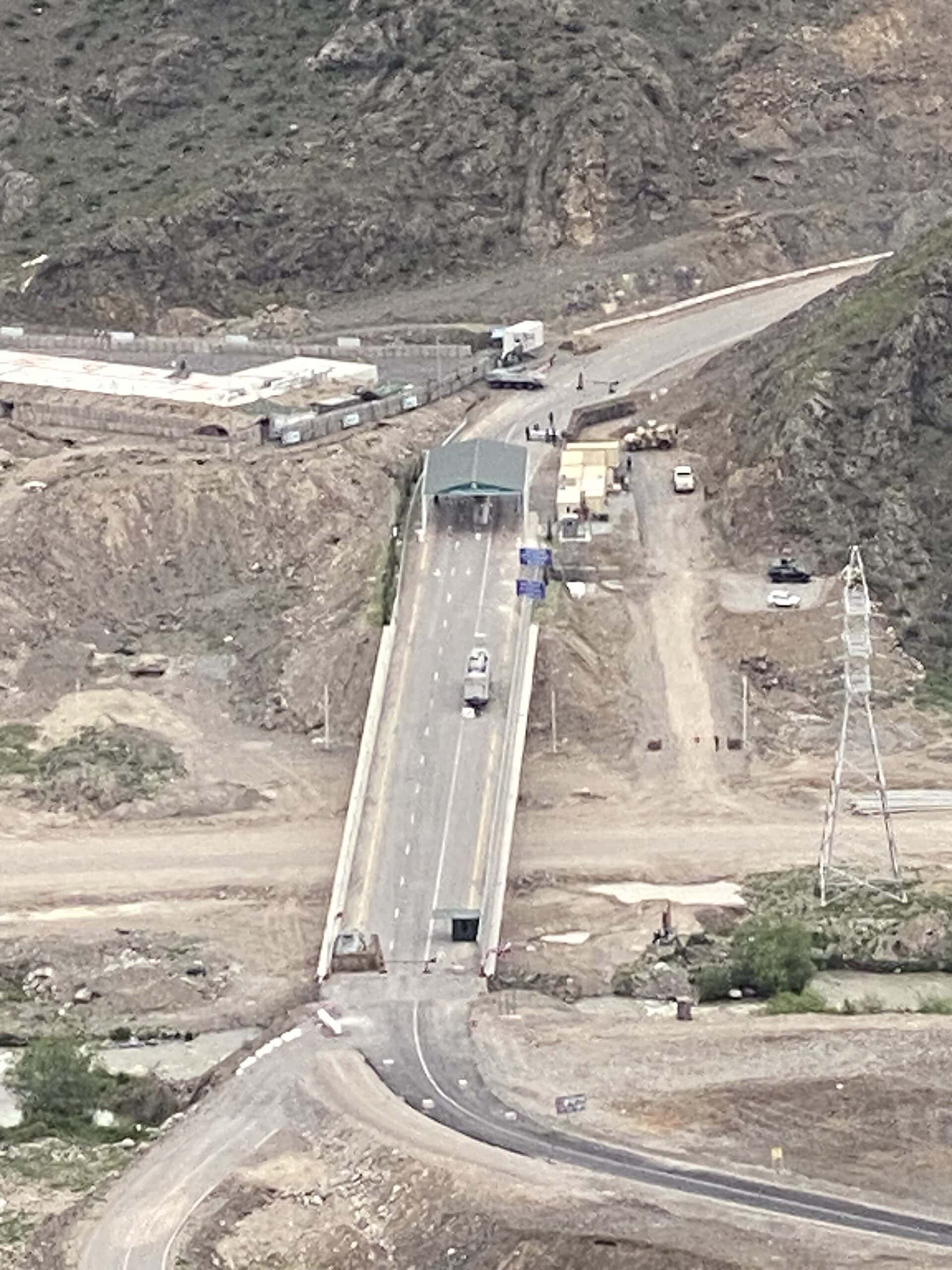 View across a valley toward a road checkpoint installed on the corridor, with hills behind