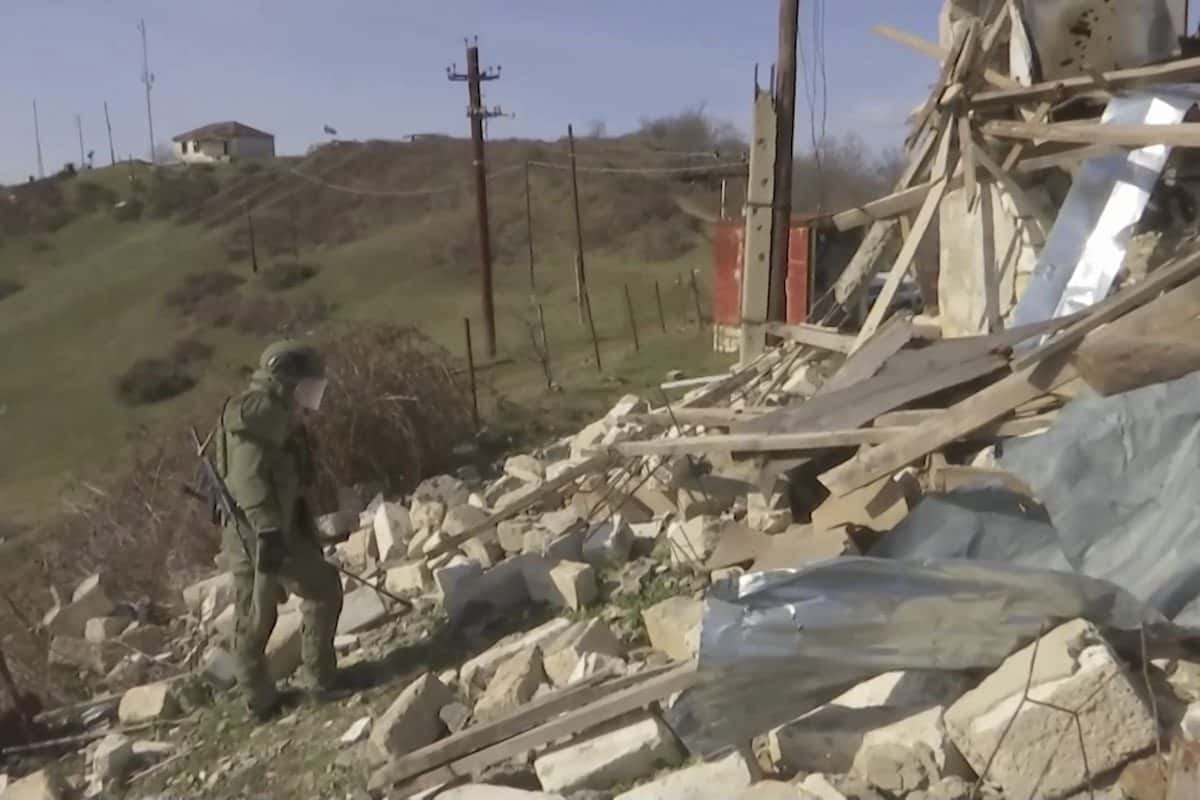 A peacekeeper in a blue helmet standing on a road in Martuni