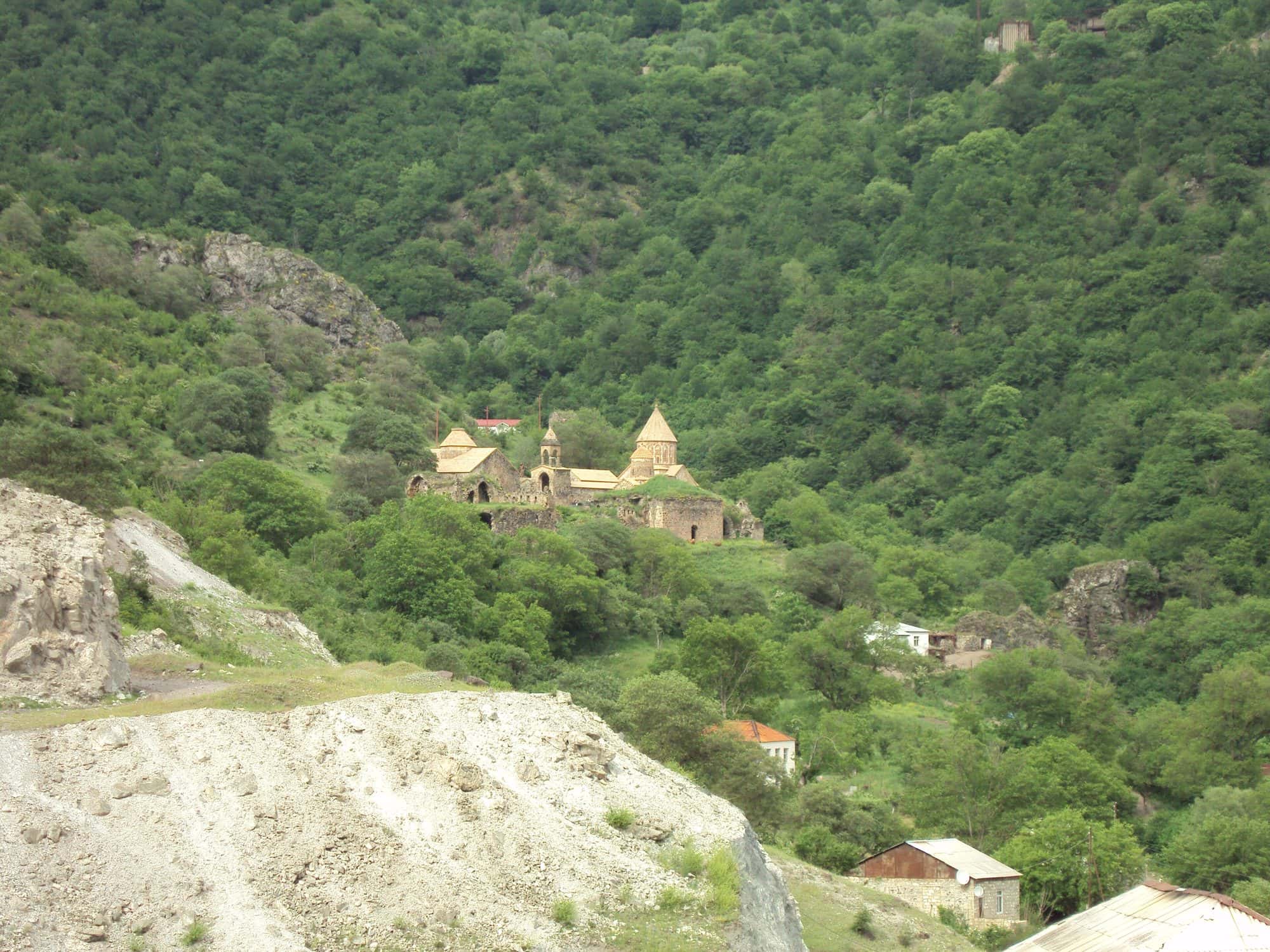 Stone Armenian monastery complex with a domed church on a wooded hillside