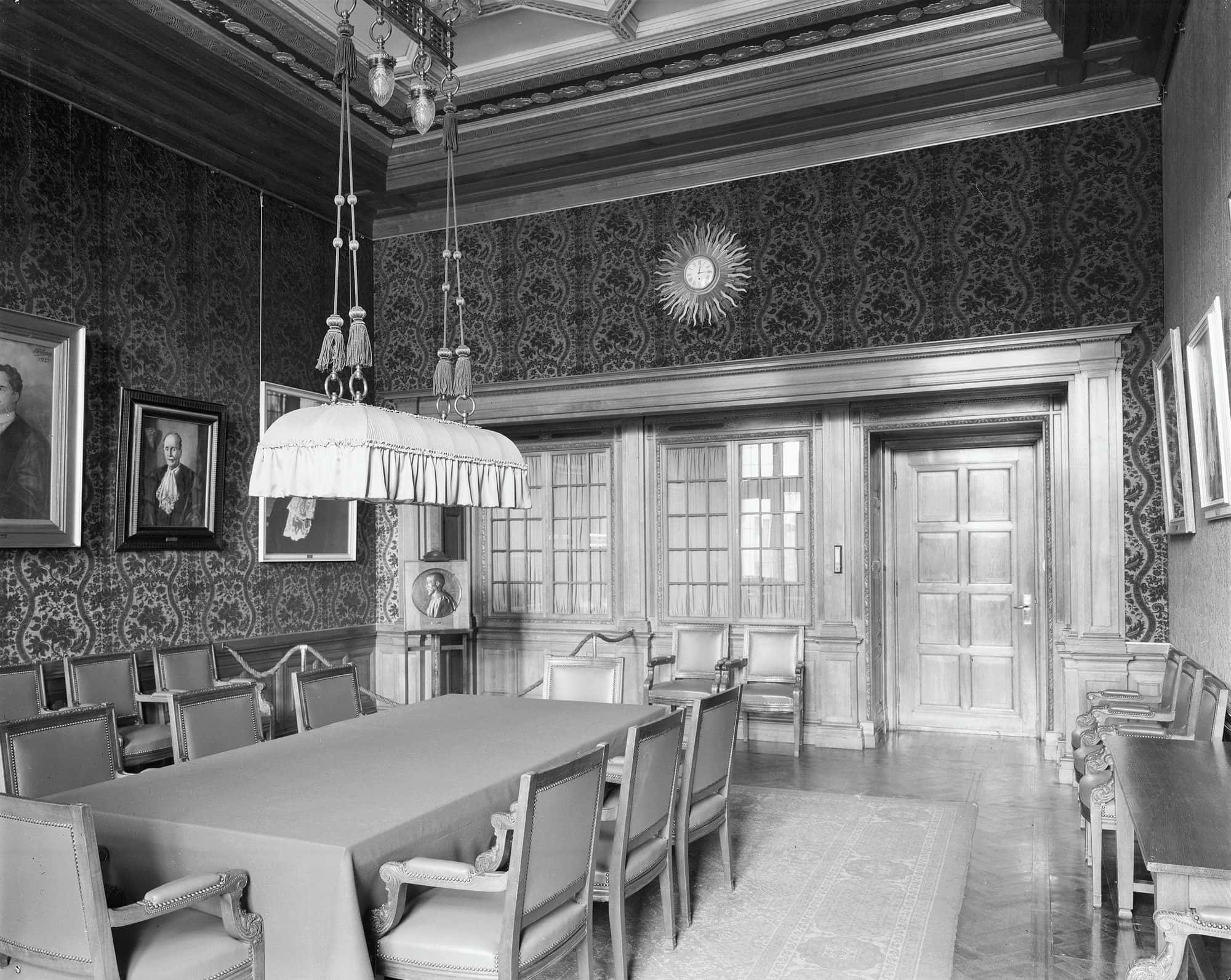 Panelled deliberation room with a long table, chairs and a fireplace